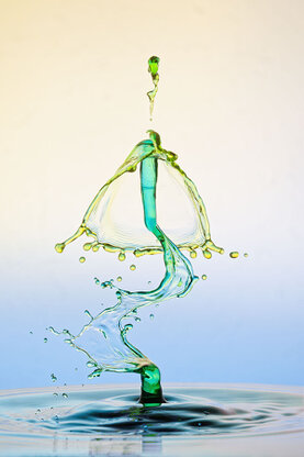 Farbige Wasserskuplturen, die aus mehreren Tropfen entstanden sind. Der Stiel wurde von Rechts und Links durch einen Luftstoß verbogen.