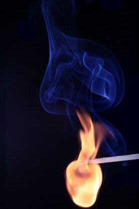 Darstellung eines zündenen Streichholzes mit Feuer und Rauch.